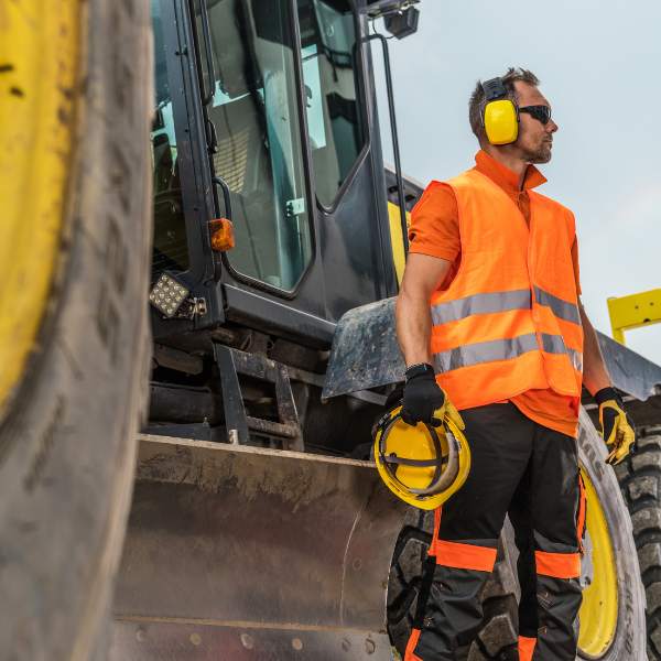 Workers using power tools while wearing ear protection, demonstrating HSEQ noise safety measures in vocational training.