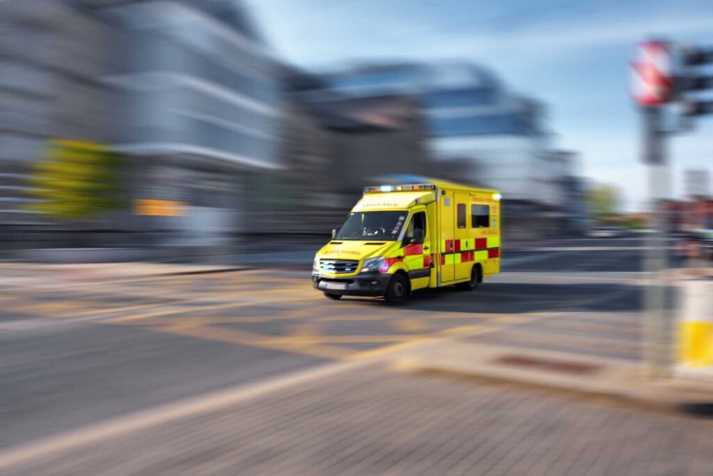 Yellow ambulance driving quickly through an urban street, representing Ireland’s upgraded emergency communication network for reliable first responder coverage.