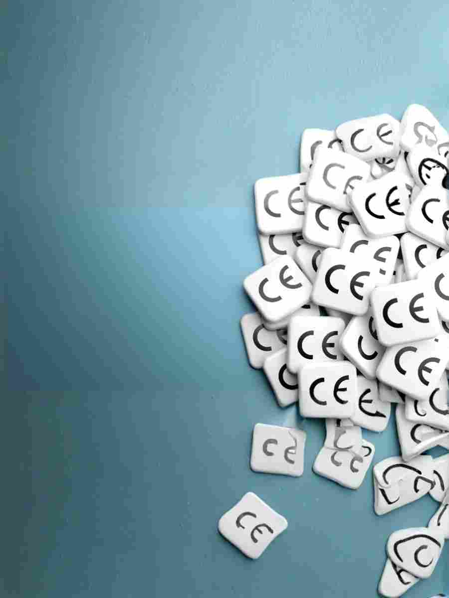 Pile of CE marking symbols on white tiles against a blue background, representing product compliance under EU regulations.